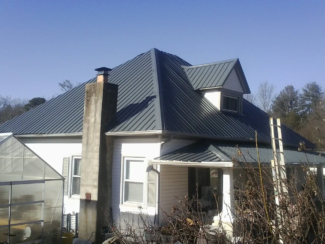 Dark blue standing seam metal roof on a white farmhouse with dormer — Slate & Tile Roof Repair by Roofing Brothers in Hammondsville