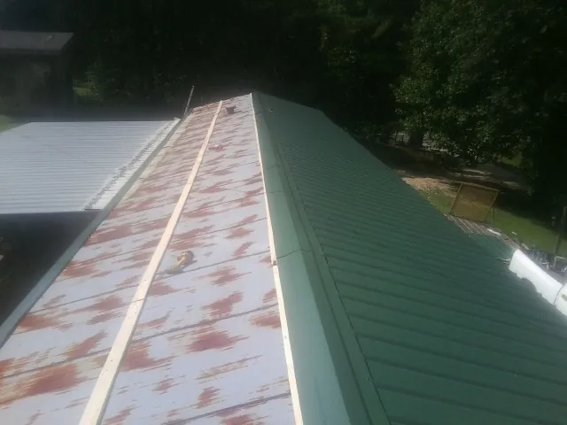 Old rusted panels beside newly installed green metal roofing — Wind Damage Roof Repair by Roofing Brothers in Hammondsville