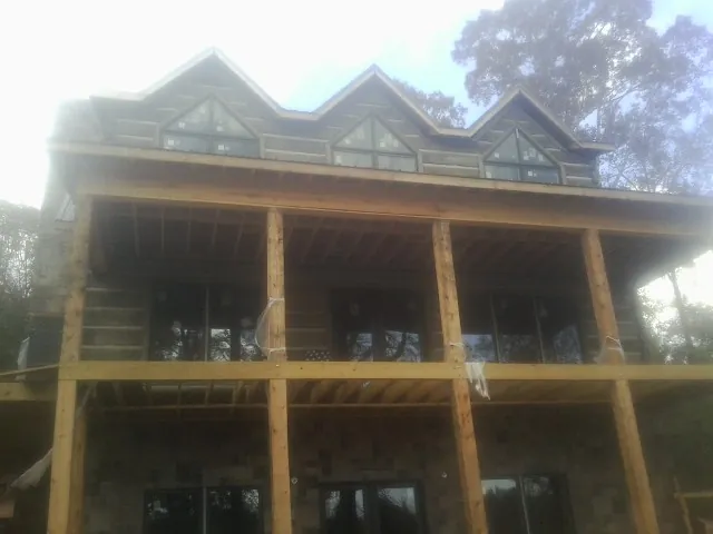 Dormers and porch framing on a large log home under construction — Roof Coating work by our crew in Hammondsville