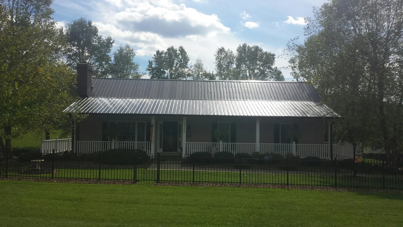 Gray metal roof on a brick ranch with a full width front porch — Gutter Guard Installation work by our crew in Hammondsville
