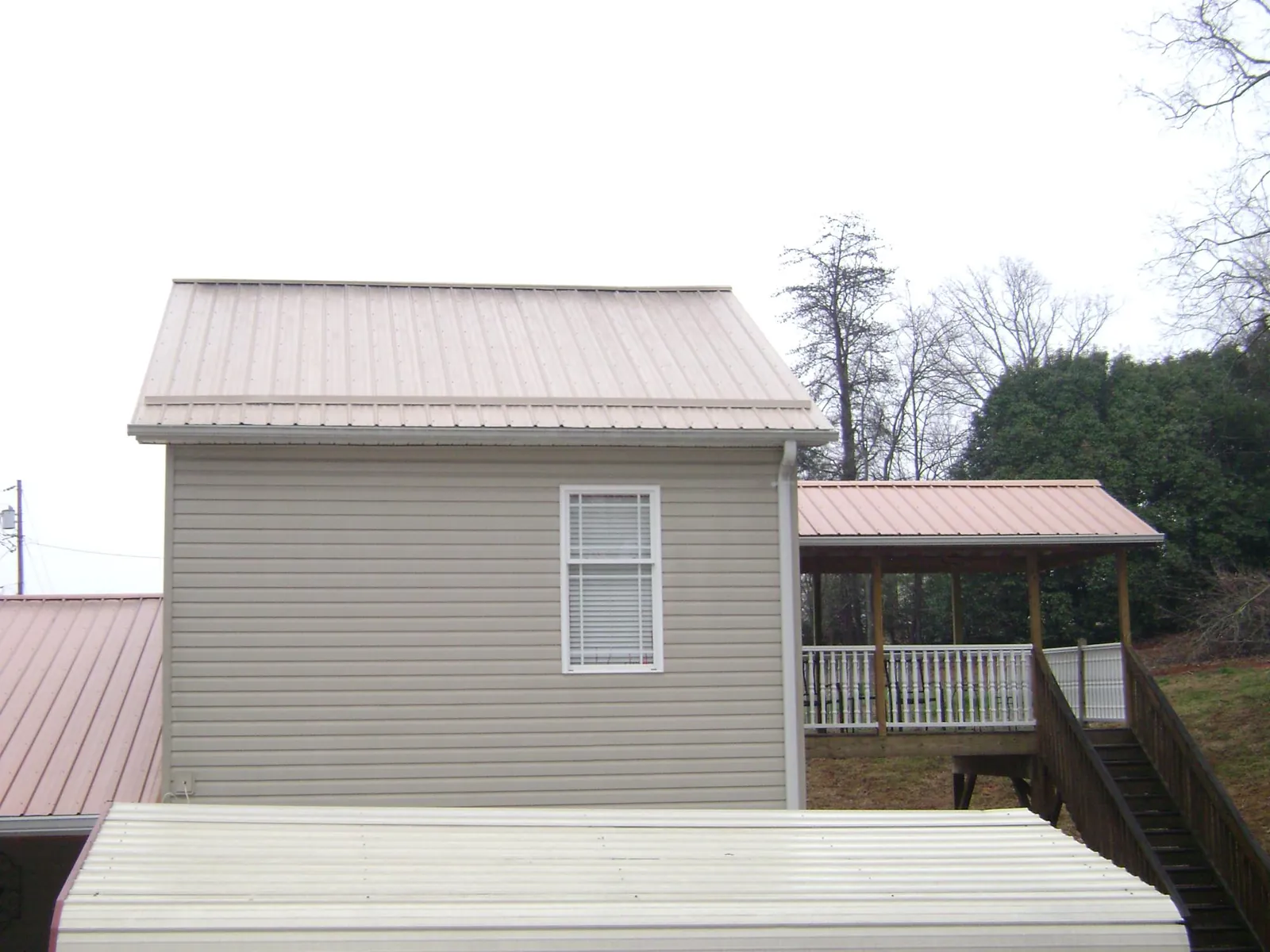Tan metal roofs on a two story addition and attached porch, from a Roof Replacement job in Hammondsville