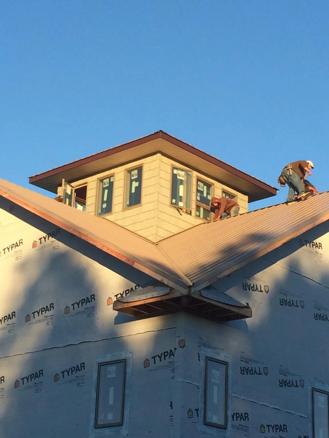 Roofers working around a rooftop cupola on a new metal roof at sunset — Roof Waterproofing in Hammondsville by Roofing Brothers
